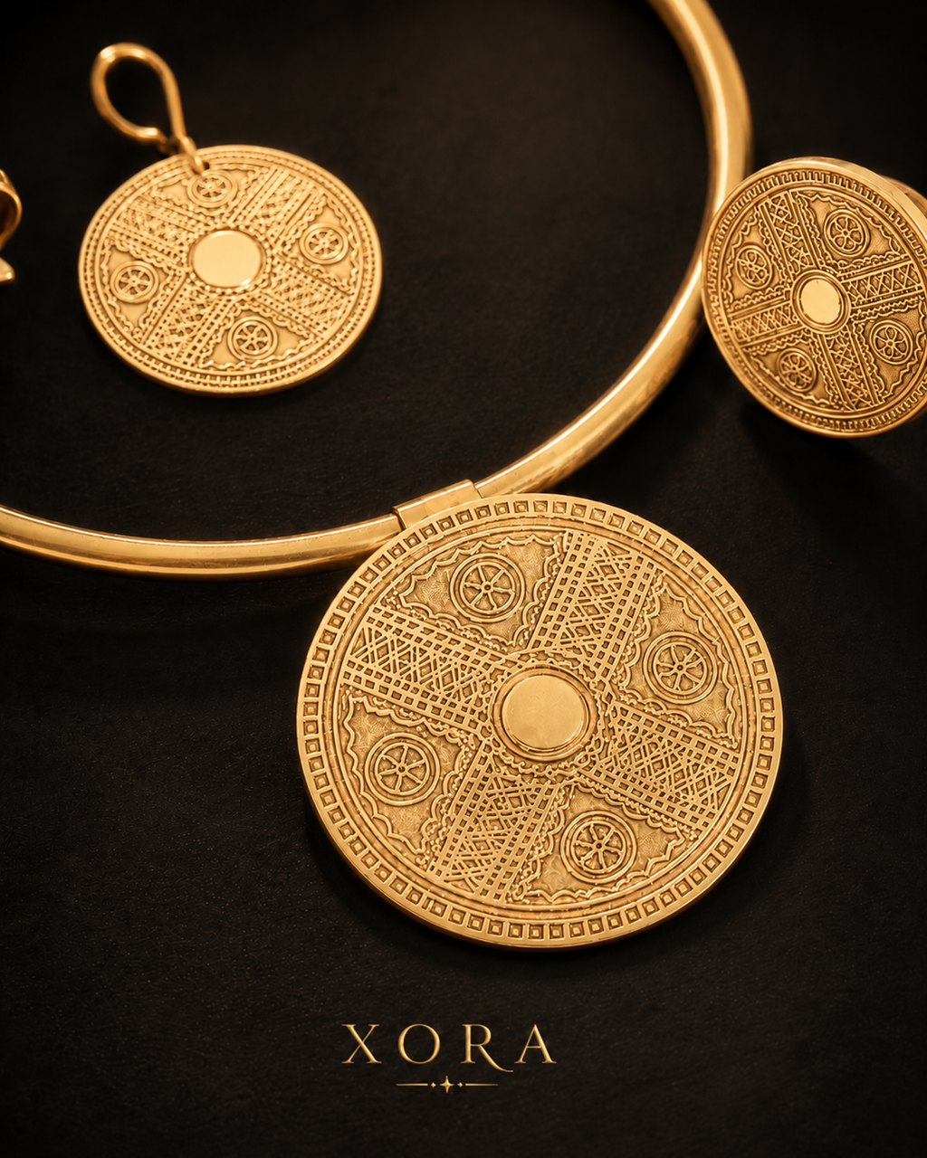 Gold-toned jewelry set with a large circular pendant, matching earrings, and a curved collar on a black background. The jewelry features intricate geometric and wheel-like engraved patterns.